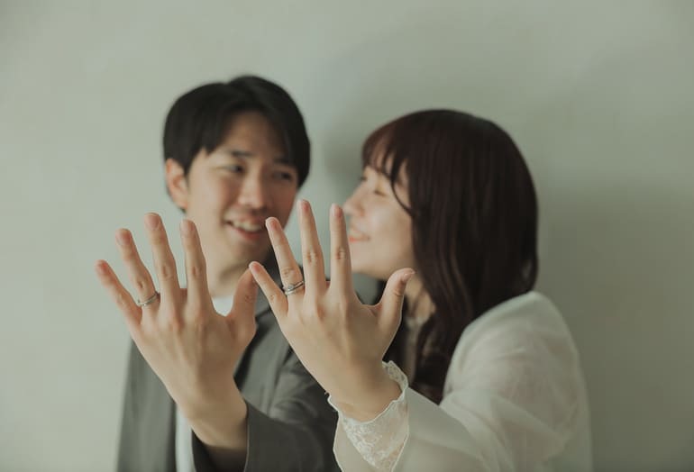 笑顔で結婚指輪を見せるカップルの入籍フォト